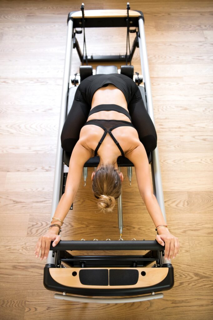 Woman doing pilates stretch on reformer bed